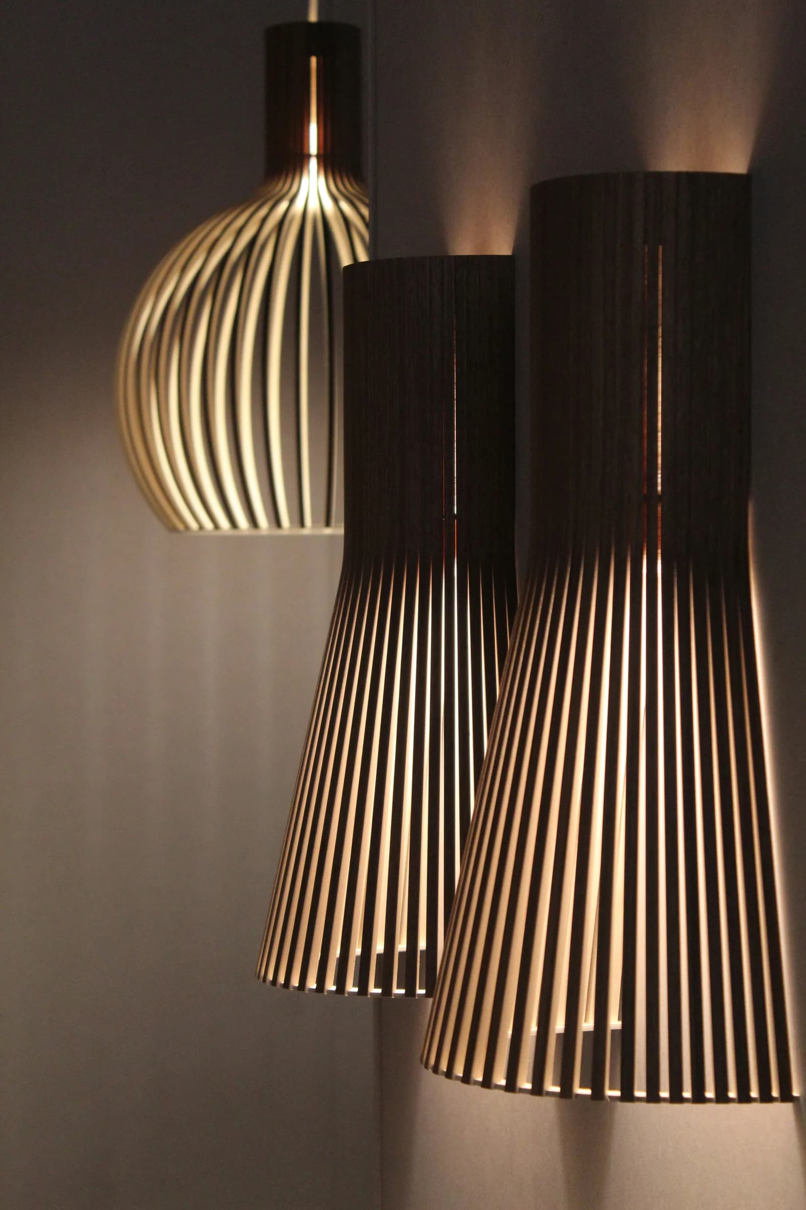 Apliques de pared de listones de madera oscura encendidos, luz cálida sobre la pared